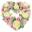This image shows a generous, heart-shaped floral tribute set against a spotless white background, its shape perfectly filled with softly coloured blooms that speak of tenderness and remembrance, much like the sympathy wreaths often requested from local Peckham florists. The heart is densely packed with flowers, dominated by creamy yellow and ivory roses whose gently unfurling petals create calm, rounded focal points throughout the design. Between them, light pink carnations cluster thickly, their frilled, ruffled petals adding a tactile richness that softens the edges of the heart and suggests comforting closeness. Deeper tones of dusky rose and mauve-pink appear in the lisianthus flowers scattered across the wreath, their open, gently cupped heads and sometimes darker centres providing subtle contrasts, like the shifting emotions that accompany grief. Weaving through and around the blossoms are sprigs of silvery-green eucalyptus, their smooth, rounded leaves bringing a cool freshness and a hint of natural woodland fragrance, reminiscent of a quiet walk in nearby Nunhead Cemetery or along tree-lined streets off Peckham Road. Tiny yellow-green buds peek out from the mass of petals, suggesting new growth and hope amid the sorrow. The composition is symmetrical and well balanced, every curve of the heart clearly defined by flowers and foliage, creating a lush, complete outline. Overall, the wreath exudes a sense of gentle peace, compassion, and enduring love, a fitting floral tribute for funerals, memorial services, or moments of reflection in Peckham, where families gather to honour cherished memories and say their final farewells.